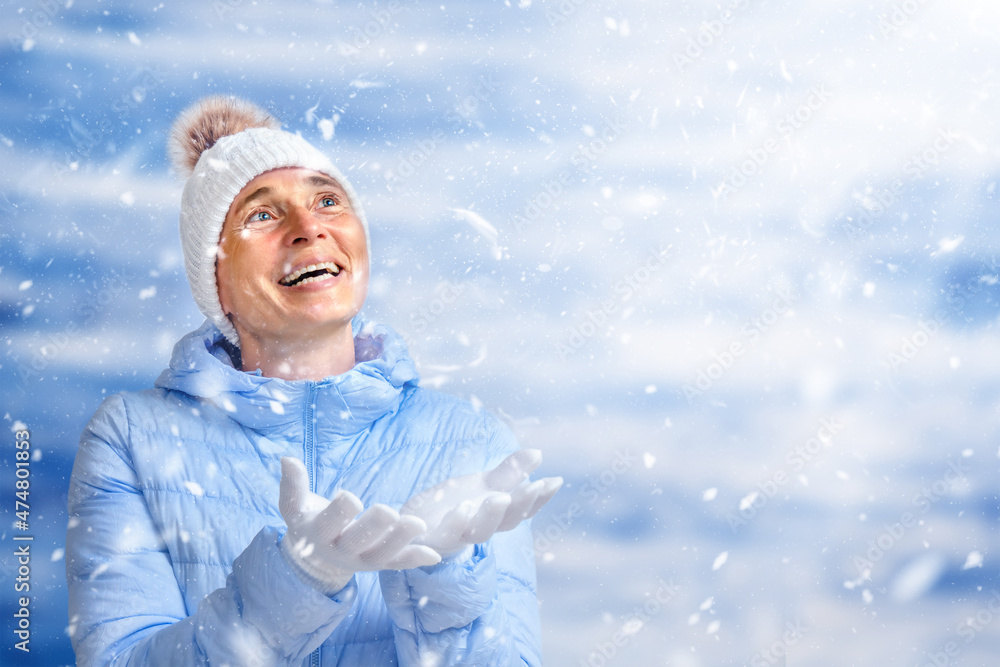 Happy senior woman catches snowflakes Happy senior woman catches snowflakes