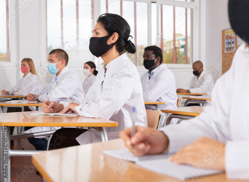 Woman studying in classroom with colleagues medicals in protective face masks for disease prevention during training program for health workers