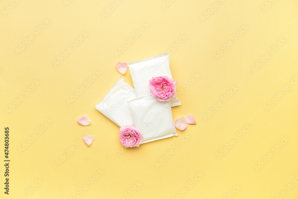 Menstrual pads and flowers on yellow background Menstrual pads and flowers on yellow background