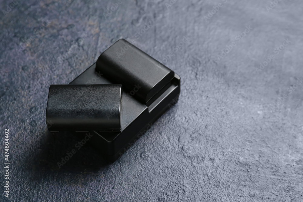 Camera batteries and charger on dark table background Camera batteries and charger on dark table background