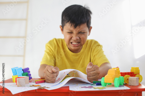 Emotional Tantrum and Angry boy while drawing on paper. Childhood traumatic experience, psychology, psychological, asperger syndrome, asperger's disorder, autistic, autism. photo