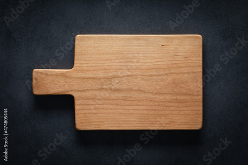 Handmade cherry wood cutting board on the dark tabletop.