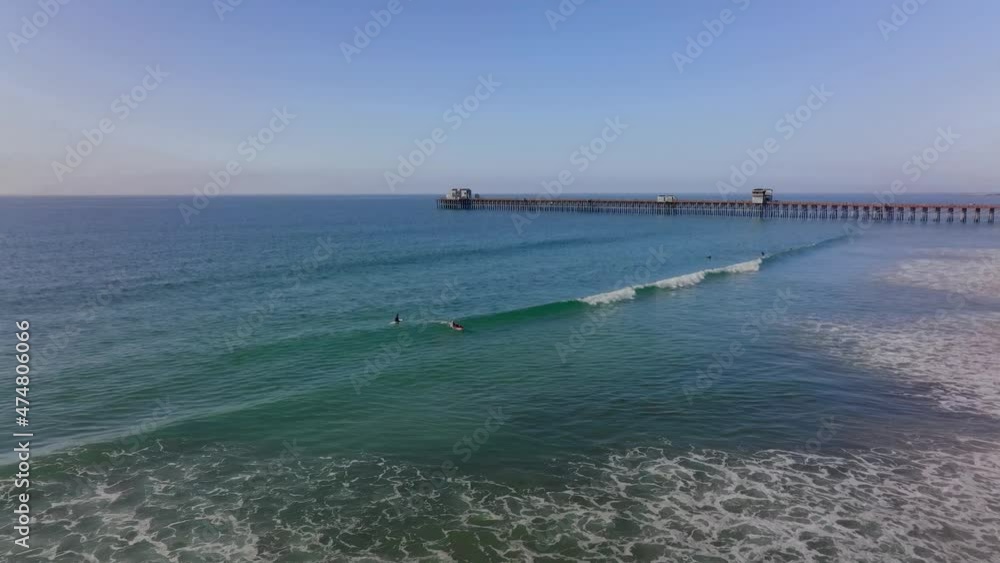 surfers riding waves at Oceanside beach, CA. historic wooden pier in background surfers riding waves at Oceanside beach, CA. historic wooden pier in background