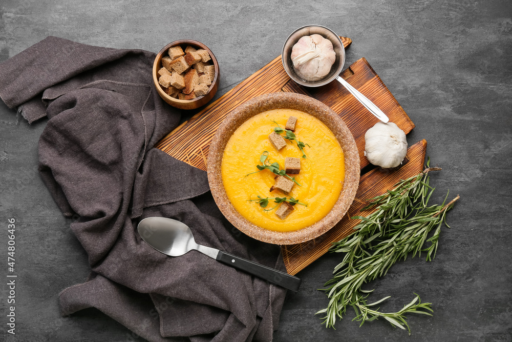 Plate of tasty pumpkin cream soup and bread on black background Plate of tasty pumpkin cream soup and bread on black background