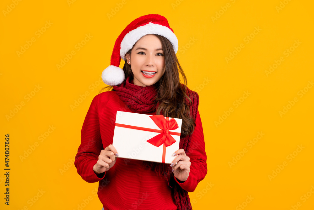 Surprised young Santa Asian woman wearing Christmas hat point index finger on gift certificate isolated on red background studio portrait. Happy New Year celebration merry holiday concep Surprised young Santa Asian woman wearing Christmas hat point index finger on gift certificate isolated on red background studio portrait. Happy New Year celebration merry holiday concep