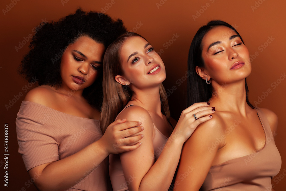 young pretty asian, caucasian, african woman posing cheerful together on brown background, lifestyle diverse nationality people concept young pretty asian, caucasian, african woman posing cheerful together on brown background, lifestyle diverse nationality people concept