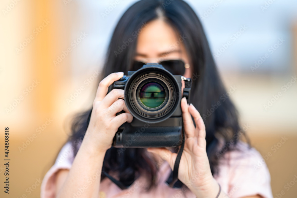 Amateur sunglasses Asian Woman take a photo with professional mirrorless camera at outdoor blue rooftop building in twilight time. Amateur sunglasses Asian Woman take a photo with professional mirrorless camera at outdoor blue rooftop building in twilight time.