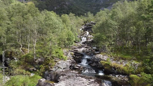 Flying very close to crispy clean river stream in between birch trees in Norway mountains - Leiro Eidslandet Norway forward moving aerial in complete wilderness photo