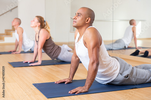 Sporty people practicing stretching yoga training in modern class