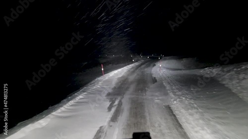 POV shot of the extreme weather conditions truck drivers have to endure during winter snow storms, as a driver cautiously travels along a snow covered road at night in Norway, Europe   photo