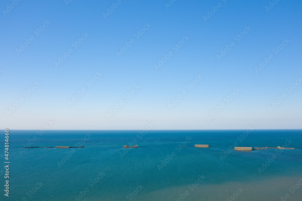 The artificial port of Gold beach in Asnelles in the middle of the English Channel in Europe, France, Normandy, Arromanches les Bains, in summer, on a sunny day.