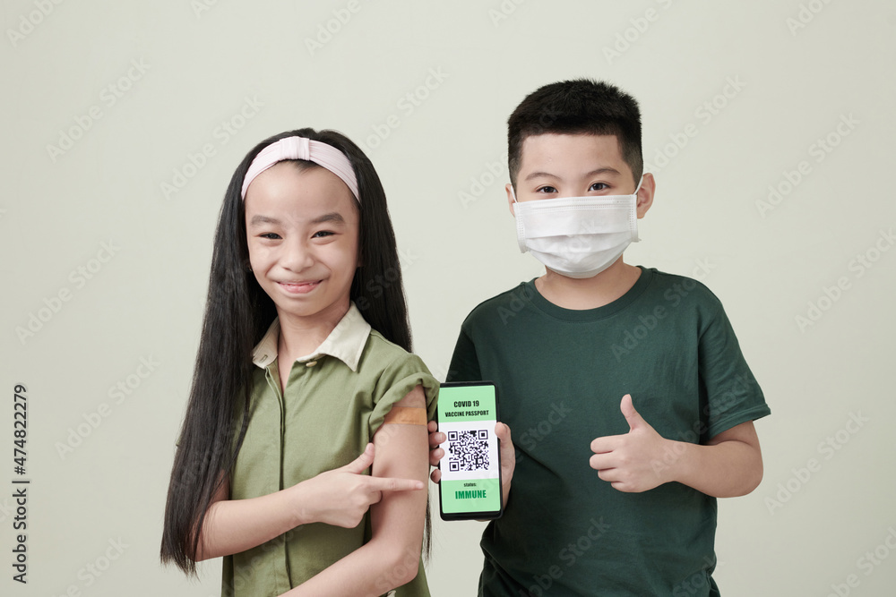 Happy little boy and girl showing smartphone with QR codes after getting vaccine against coronavirus Happy little boy and girl showing smartphone with QR codes after getting vaccine against coronavirus