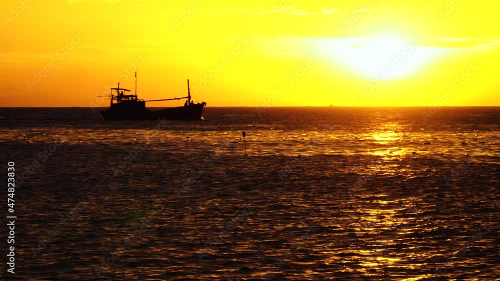 Silhouette of fishing boat returning home during golden sunset time, static view Silhouette of fishing boat returning home during golden sunset time, static view