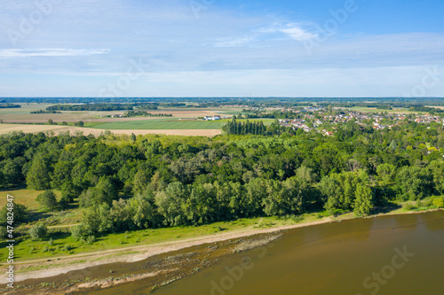 The green countryside towards the town of Sully sur Loire in Europe, in France, in the Center region, in the Loiret, in summer, on a sunny day.