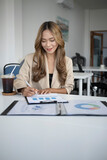 Portrait of beautiful businesswoman analyzing financial graphs charts in office.