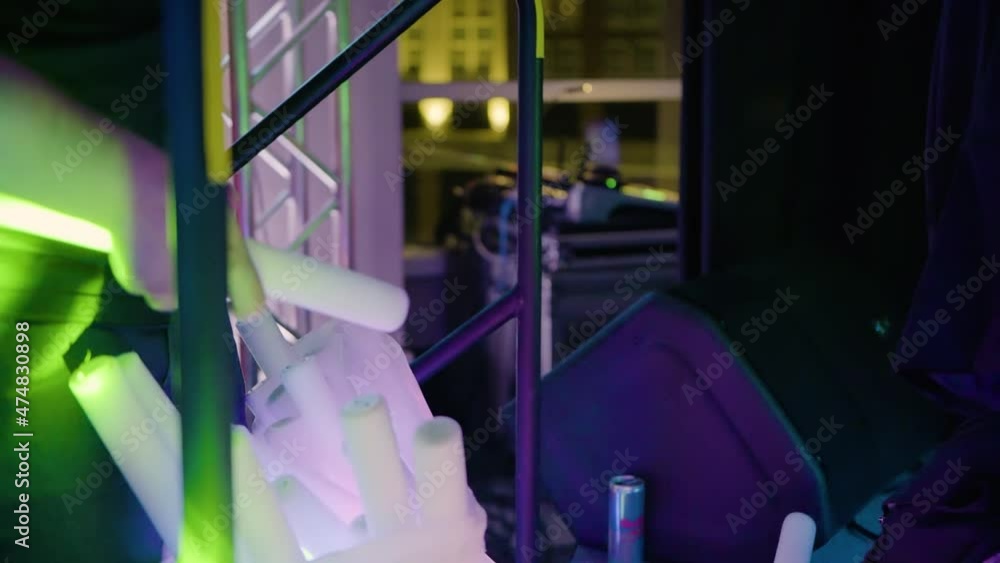 Hands putting used glow sticks inside bag during event, backstage. Gimbal, close up Hands putting used glow sticks inside bag during event, backstage. Gimbal, close up