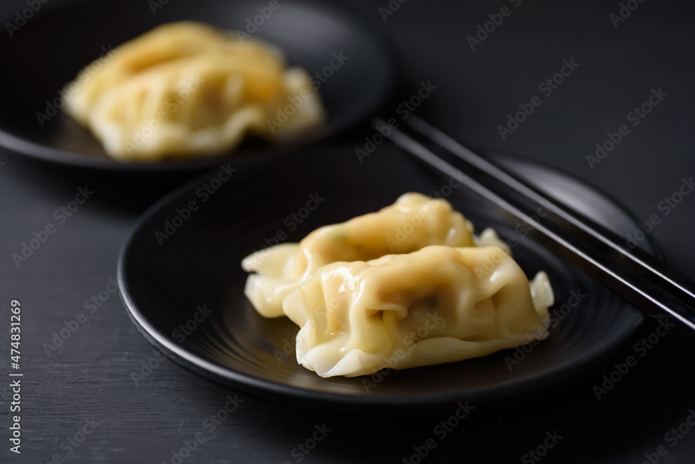 Wonton stuffed, gyoza or dumplings, Asian cultural food on black background Wonton stuffed, gyoza or dumplings, Asian cultural food on black background