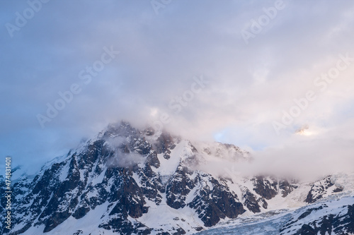 The Aiguille du Midi in the middle of the colorful clouds in the Mont Blanc massif in Europe, France, the Alps, towards Chamonix, in summer, on a sunny day.
