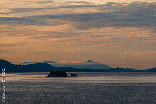 golden hour by the sea with silhouette of islands over the horizon under cloudy sky