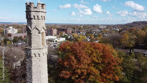 Aerial circular pan around historic watchtower of battlefield monument at stoney creek battlefield park, Hamilton city, Ontario Canada, capturing beautiful surrounding townscape and landscape.