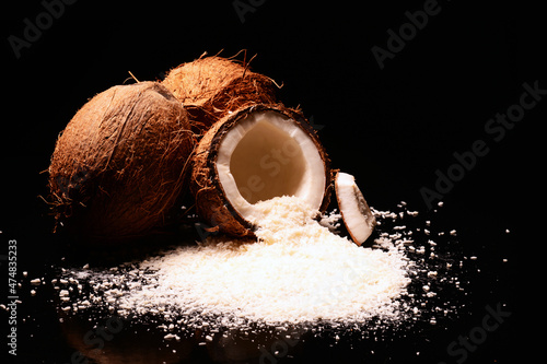 Wiórki kokosowe i kokos. Skorupa orzecha kokosowego z płatkami kokosowymi i czarnym tłem. Kokosy na każdą okazję i produkt, kosmetyki, żywność, beauty, potencje. Miłość i czułość