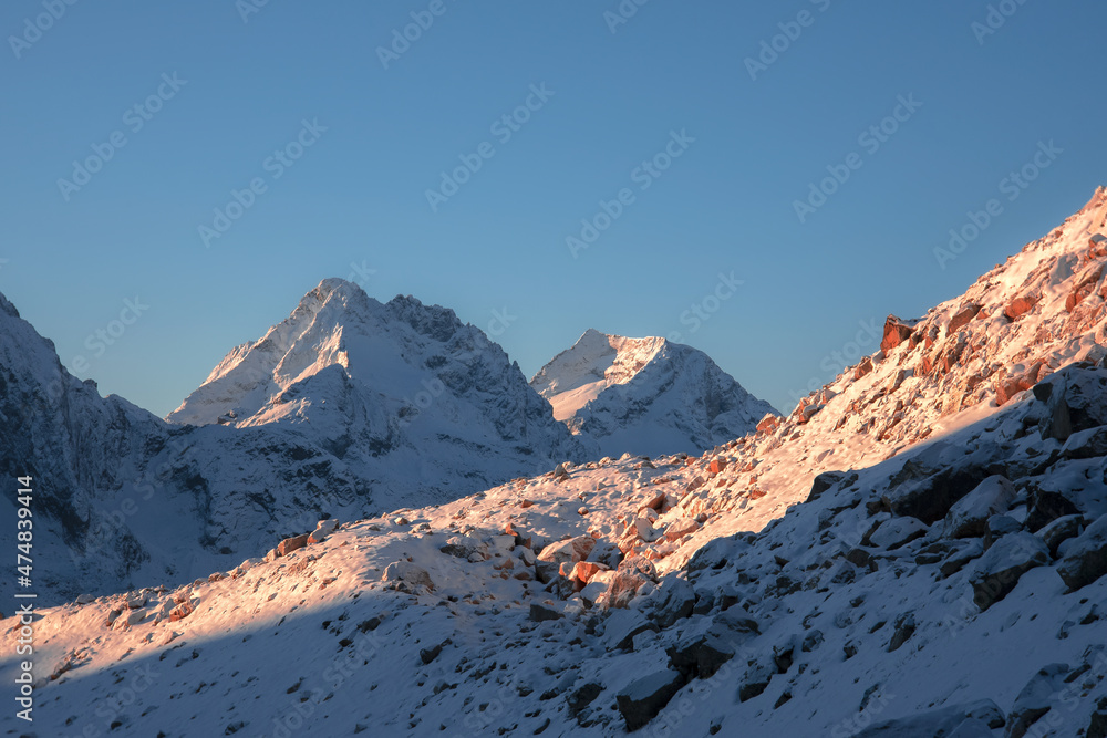 mountain peaks and slopes in snow in the early morning with the first rays of the sun