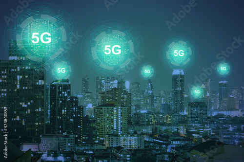 Creative dark night city wallpaper with glowing 5G circuit hologram. Internet speed, ubanization, communication and connection concept. Double exposure.