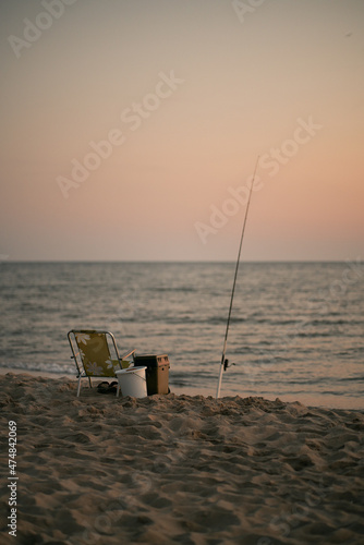 Sitting and fishing pole on coastline during sunset. No man fishers place on the seaside at the summer evening