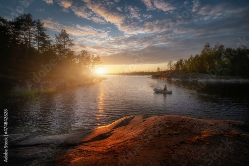 Sunny summer sunset on Lake Ladoga. Colorful clouds. Quiet and peaceful evening. Beautiful light falls on rocks and moss. Ladoga. Republic of Karelia.