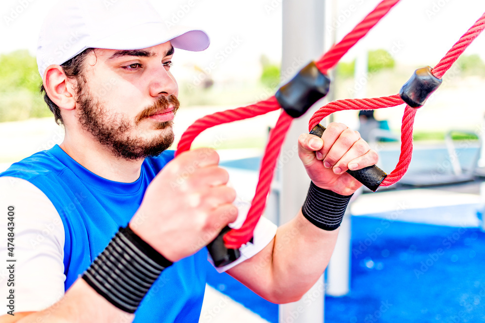 Portrait of man during workout with suspension straps In calisthenic park. Portrait of man during workout with suspension straps In calisthenic park.