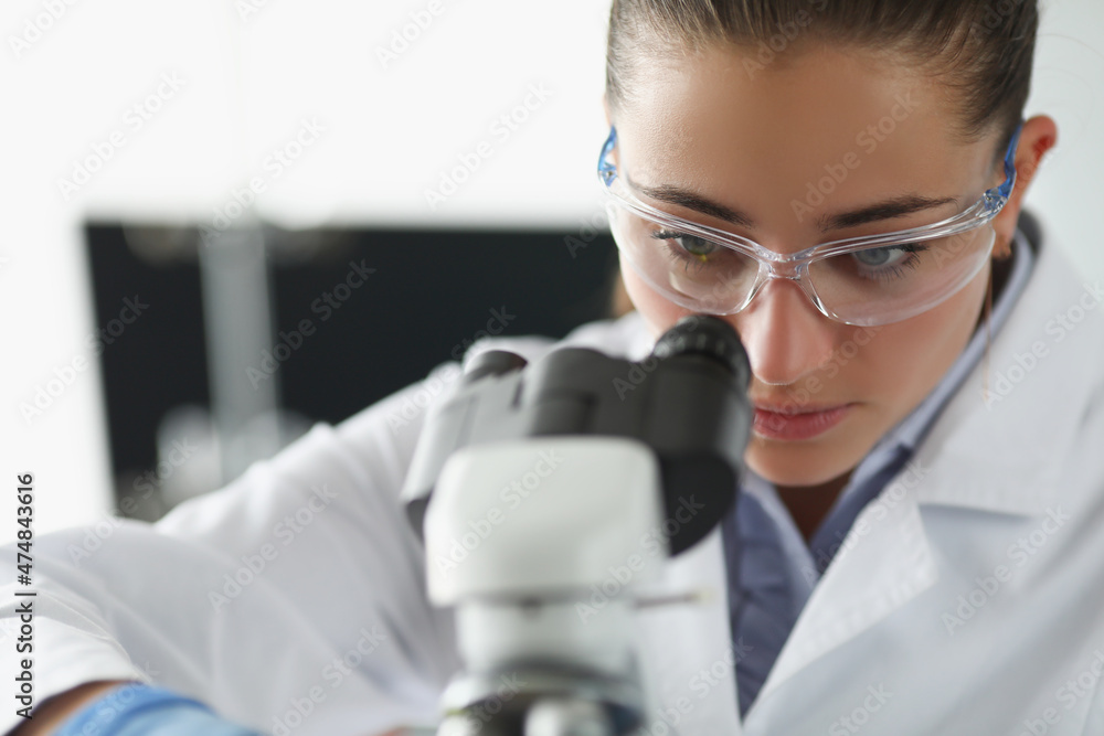 Female chemist investigate sample under microscope equipment in lab Female chemist investigate sample under microscope equipment in lab