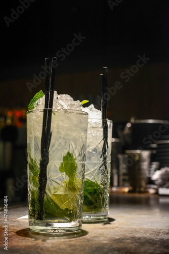 two mojitos with black tubes on the bar
