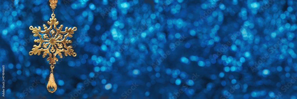 Christmas ornaments. golden snowflake pendant on Christmas tree defocused blue bokeh background. Happy new year greeting card. Copy space wide banner. Selective focus