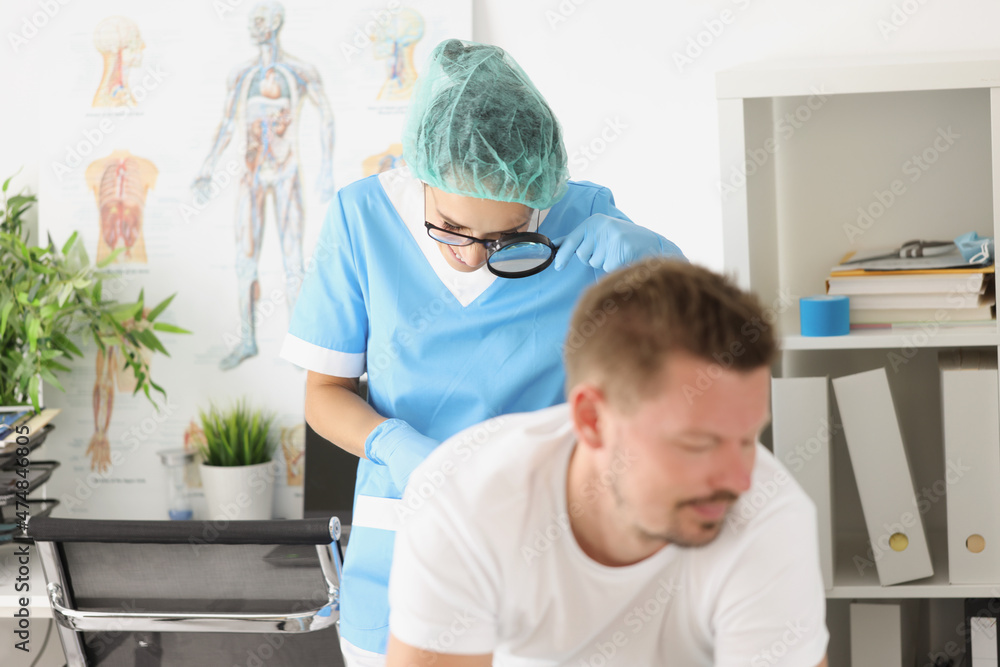 Fototapeta premium Dermatologist doctor examines mole on patients body with magnifying glass