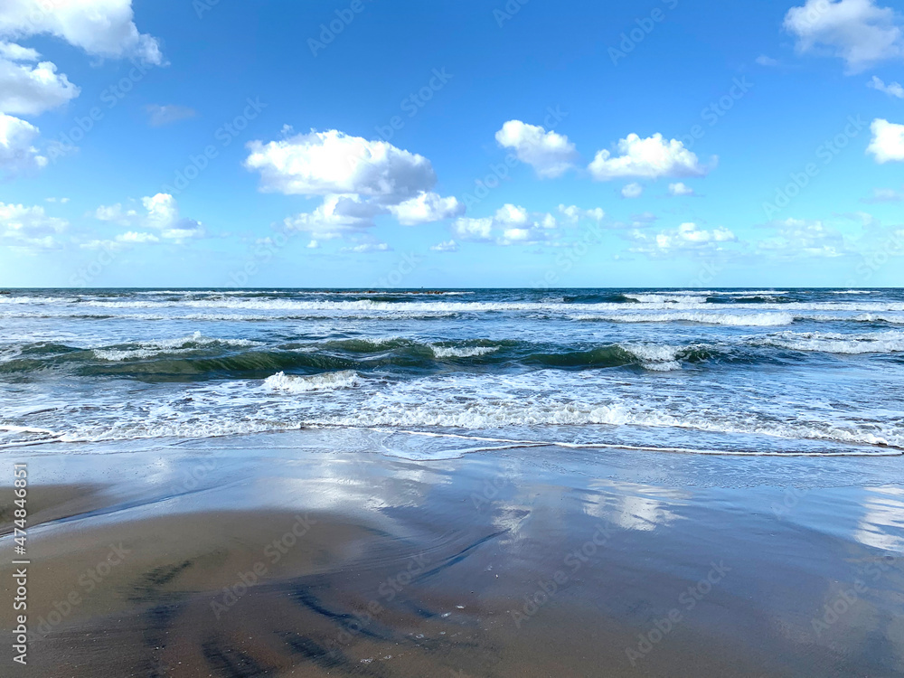 The sea coast with the reflection of white clouds on the sand The sea coast with the reflection of white clouds on the sand