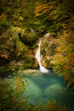waterfall over turquoise lake and wrapped in fall foliage with oranges and browns