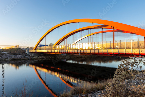 curved red arches of the highway bridge over the river Lech near Augsburg in the light of the evening sun
