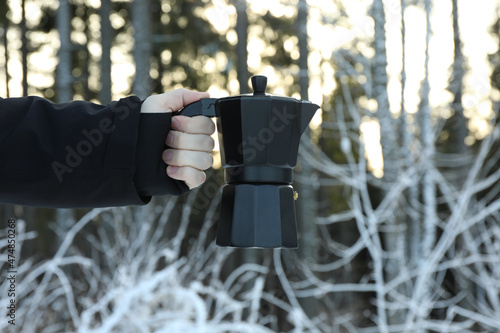 Male hand holds coffee maker in forest