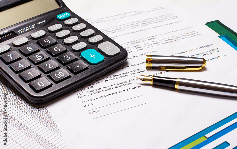 On the desktop, a calculator, documents and a fountain pen. Business concept. Workplace close up On the desktop, a calculator, documents and a fountain pen. Business concept. Workplace close up