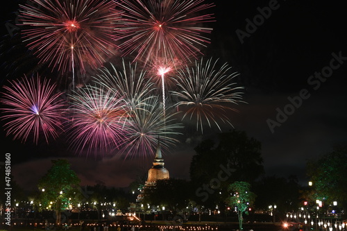Multicolored firework near the old principal Buddha image,old pagoda on the celebration Loy Krathong festival at the Wat Mahathat Temple in Sukhothai Historical Park.It is a tradition around ancient 