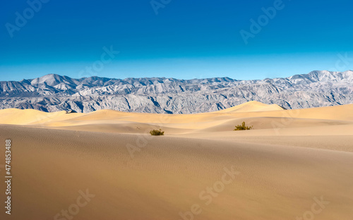 Deserted landscape. Sand dunes and desert rocky mountains. Sand dunes against a blue sky.