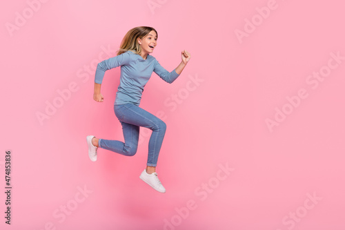 Full size profile side photo of young excited girl run energetic look empty space hurry isolated over pink color background