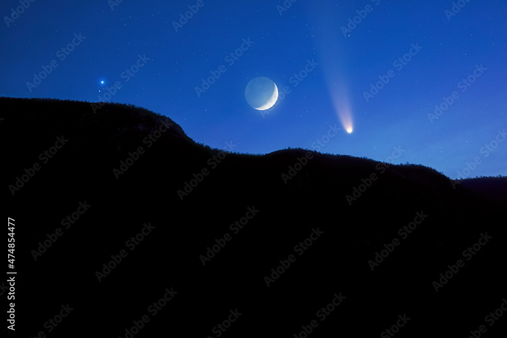 Crescent Moon, comet and stars above mountain silhouette.