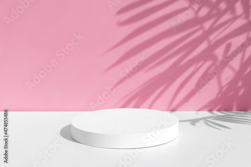Minimal abstract pink and white background for eco cosmetic product presentation. Cylindrical white scene. Premium podium with a shadow of tropical palm leaves. Empty showcase.