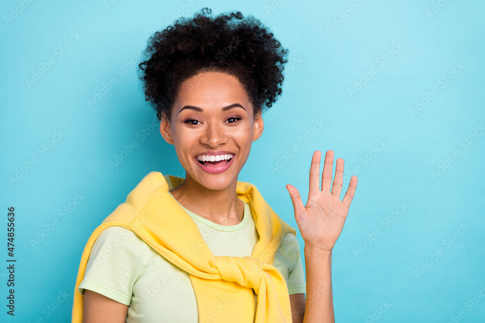 Photo of young cheerful african woman good mood see friends wave hi isolated over blue color background