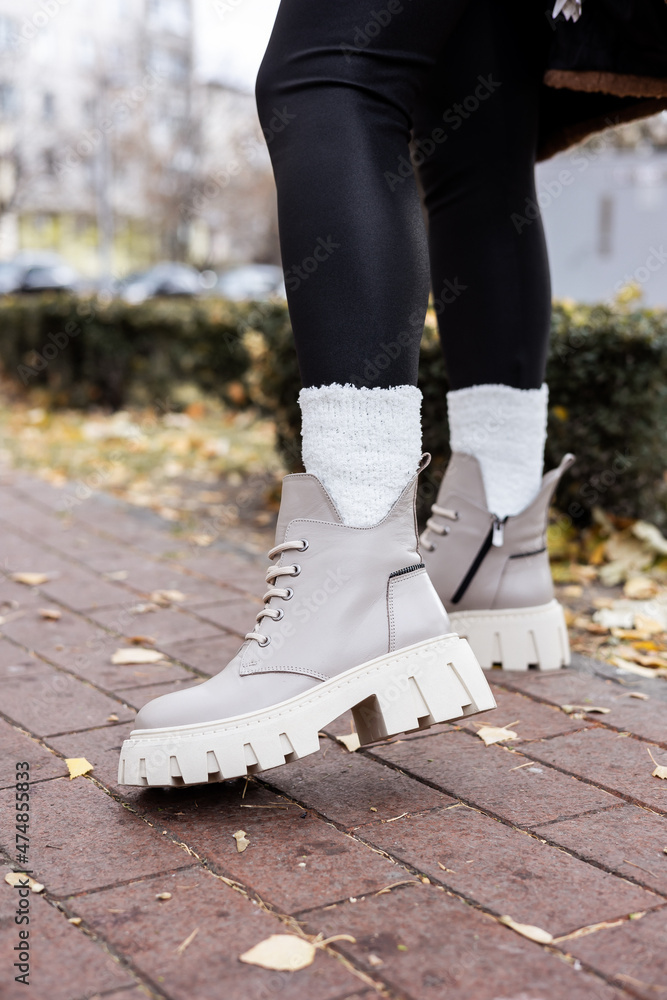 Stylish woman stands in beige shoes. Close-up of female legs in fashionable leather beige vintage boots. New seasonal collection of women's shoes
