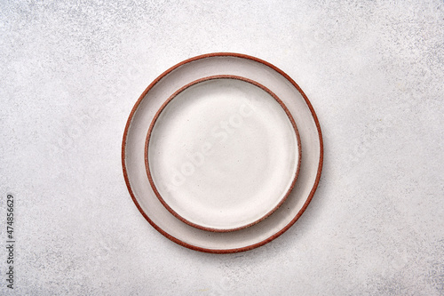 Empty two one in one white ceramic plates with brown rim on a light textured background, top view, copy space