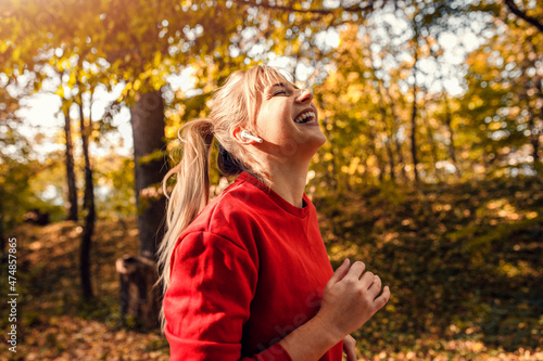 Smiling young woman running in park.