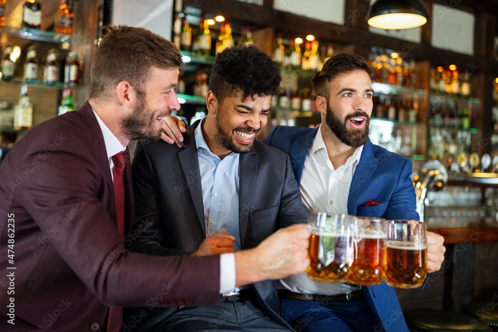 Team of colleagues socializing at the bar and drinking beers Team of colleagues socializing at the bar and drinking beers