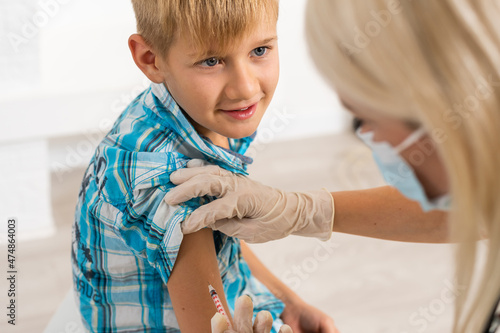 Female doctor making injection to little boy photo